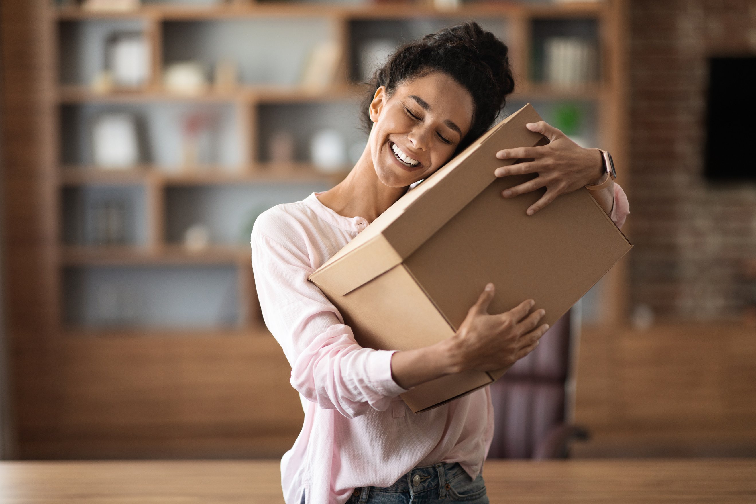 Delighted woman customer hugging paper box parcel